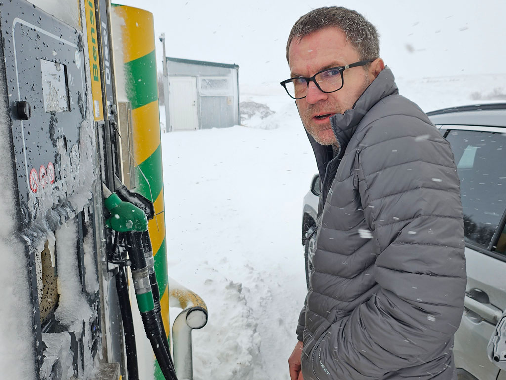 dirk an einer vereisten zapsäule im schneesturm, island, märz 2024